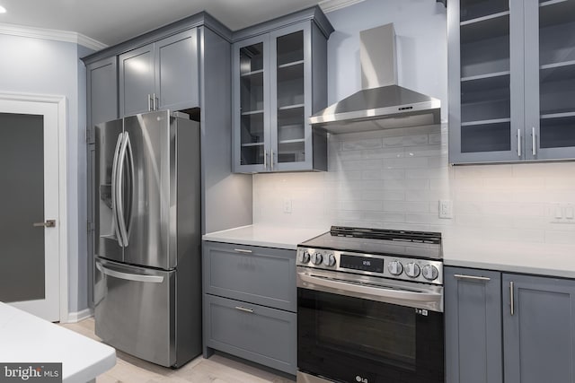 kitchen featuring decorative backsplash, appliances with stainless steel finishes, gray cabinets, and wall chimney range hood