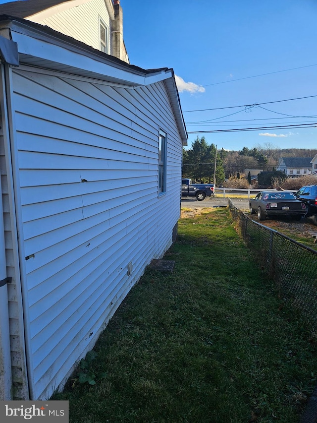 view of property exterior featuring a lawn and fence