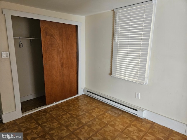 unfurnished bedroom with baseboards, baseboard heating, and a closet