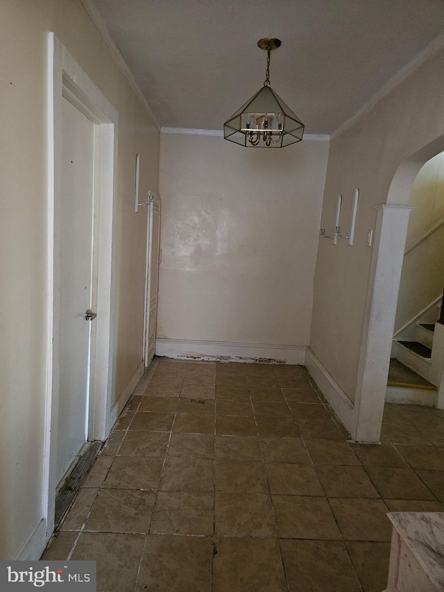 unfurnished dining area with baseboards, stairs, arched walkways, and crown molding