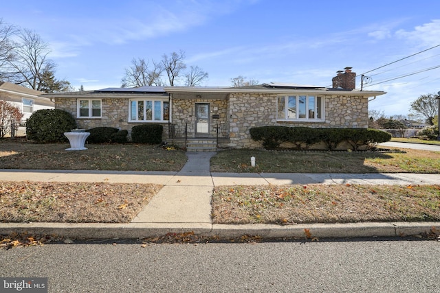 view of front of property featuring a chimney and solar panels