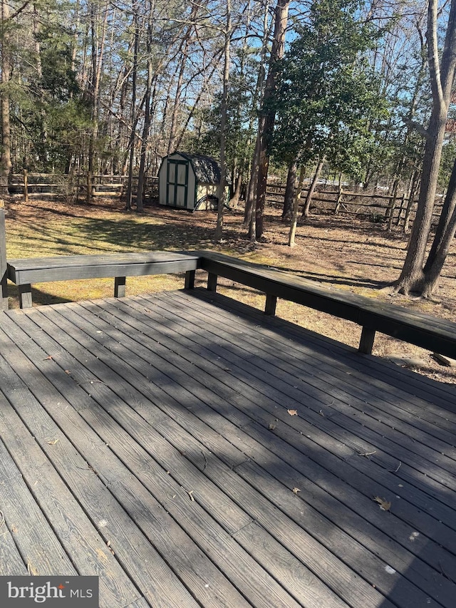 wooden deck featuring a shed, fence, and an outdoor structure