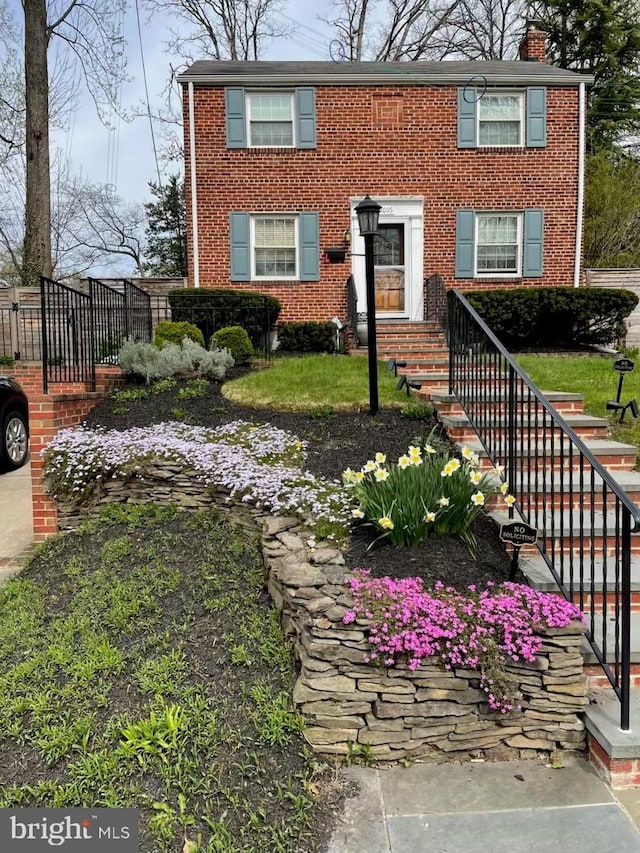 view of front facade featuring brick siding and a chimney