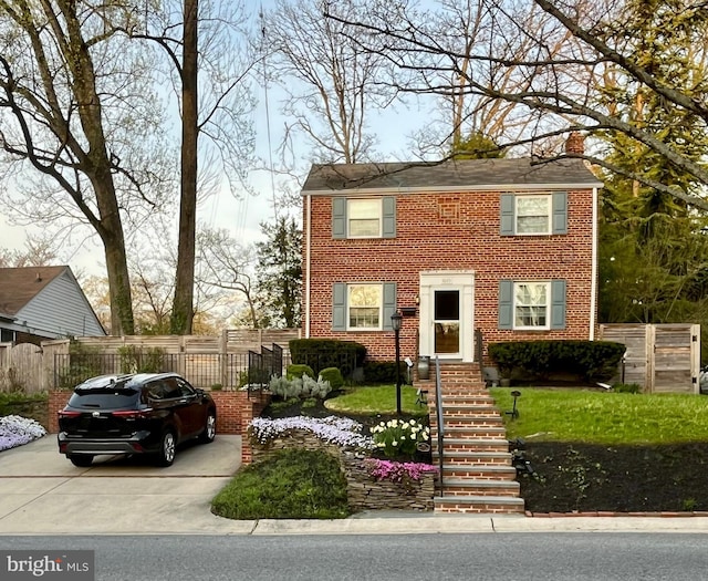 colonial house with brick siding, a chimney, and fence