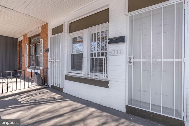 property entrance with a porch and brick siding