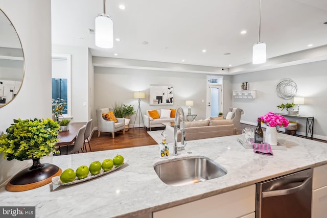 kitchen with a sink, light stone counters, stainless steel dishwasher, open floor plan, and recessed lighting