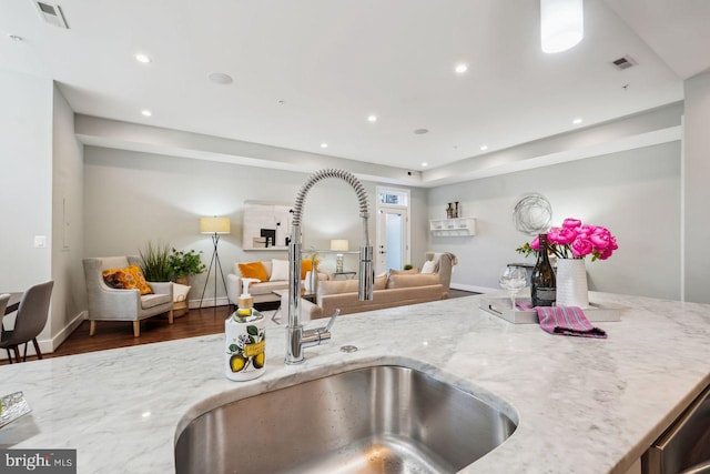 kitchen with light stone counters, visible vents, recessed lighting, a sink, and open floor plan