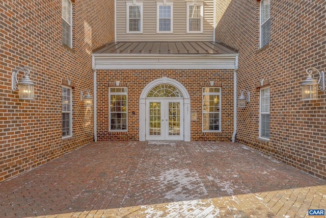 doorway to property with french doors, brick siding, a patio, a standing seam roof, and metal roof