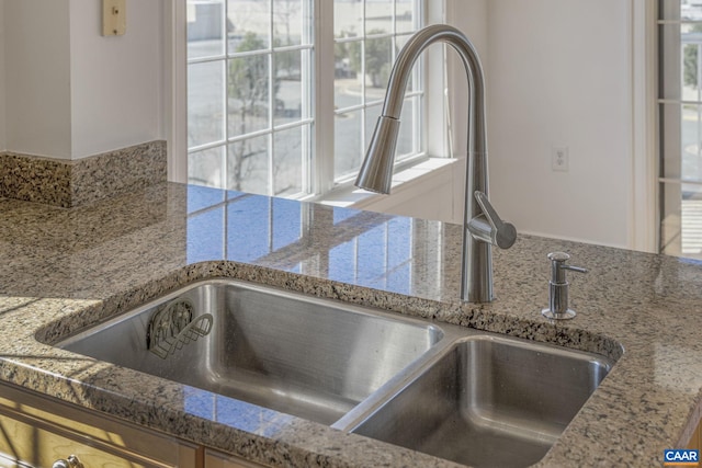 room details with light stone countertops and a sink