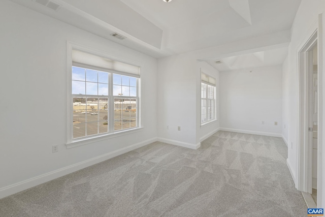 spare room with light carpet, baseboards, visible vents, and a raised ceiling