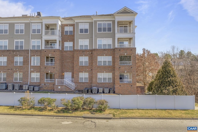 view of building exterior with central AC unit and fence