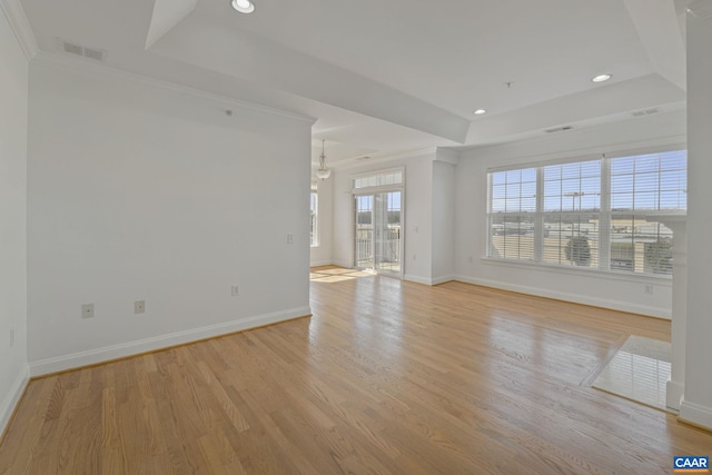 empty room featuring recessed lighting, baseboards, ornamental molding, light wood finished floors, and a raised ceiling