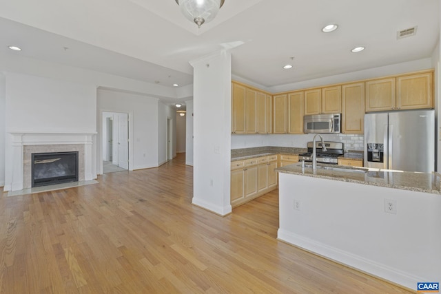 kitchen with appliances with stainless steel finishes, light brown cabinets, and light wood-style flooring