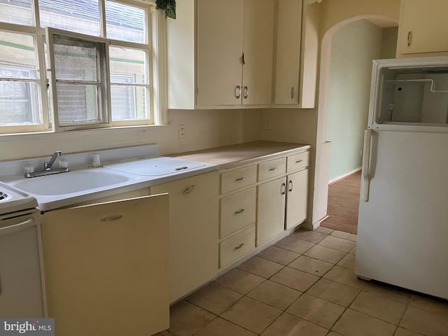 kitchen featuring white appliances, light countertops, a sink, and light tile patterned floors