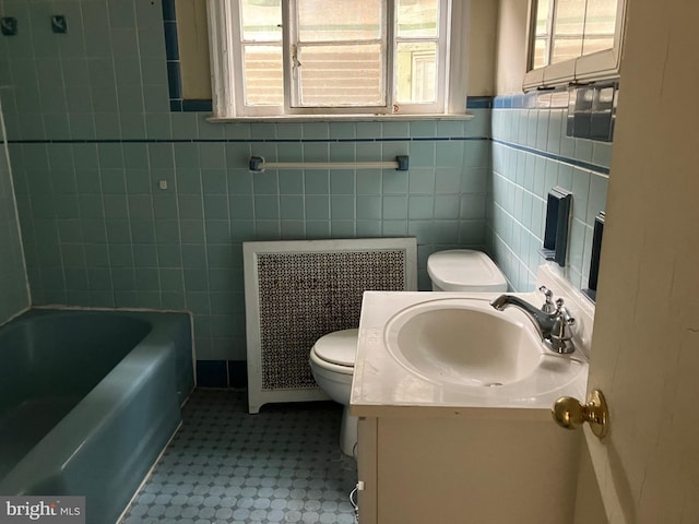 bathroom featuring a washtub, toilet, tile walls, vanity, and radiator