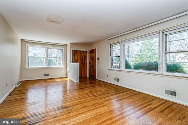 empty room with visible vents, plenty of natural light, and light wood-style floors