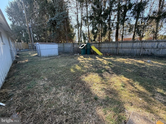 view of yard with an outdoor structure, a playground, a storage unit, and a fenced backyard