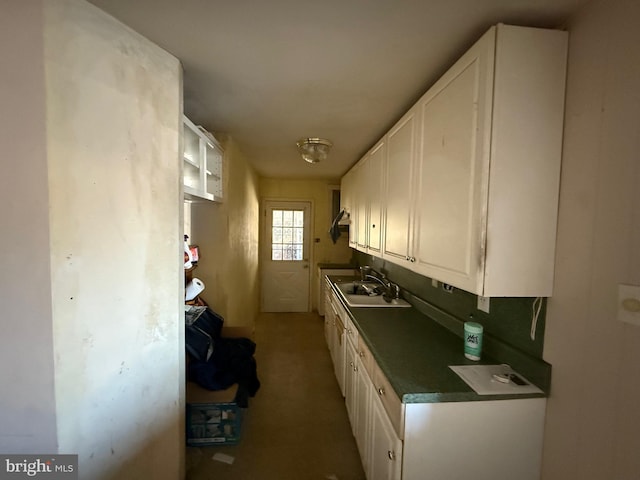 kitchen with dark countertops, white cabinets, and a sink