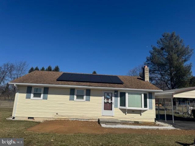 view of front of property with a carport, crawl space, a chimney, and roof mounted solar panels