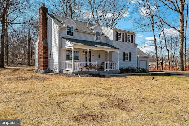 view of front of home featuring a porch, a shingled roof, an attached garage, a front yard, and a chimney