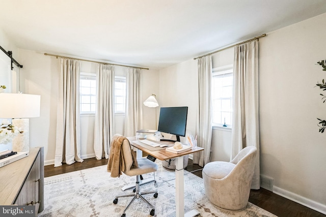 office with a barn door, dark wood-style floors, baseboards, and a wealth of natural light