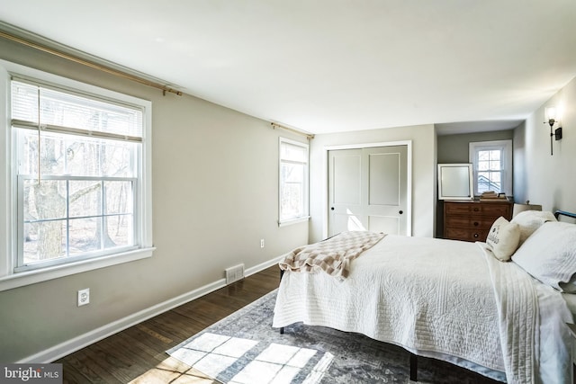 bedroom featuring baseboards, multiple windows, and wood finished floors