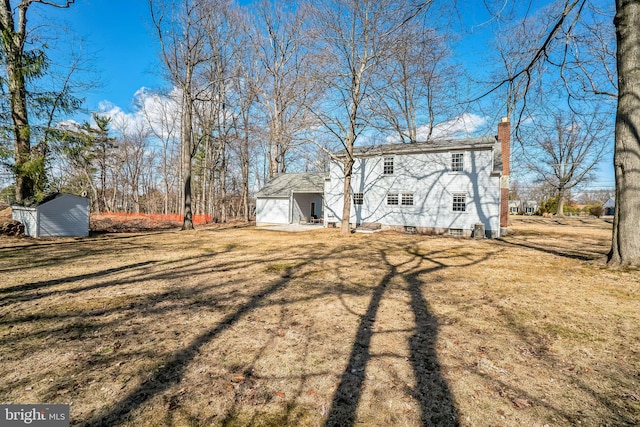 back of property with a chimney, a yard, and an outdoor structure