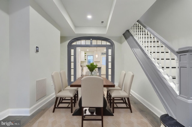 dining area with stairs, a tray ceiling, baseboards, and visible vents