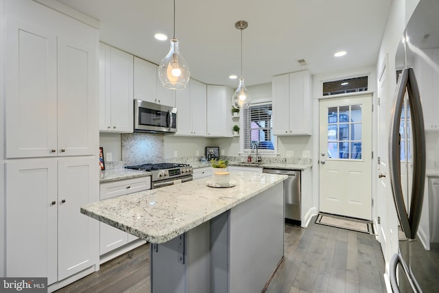 kitchen with stainless steel appliances, a kitchen island, dark wood finished floors, and white cabinets