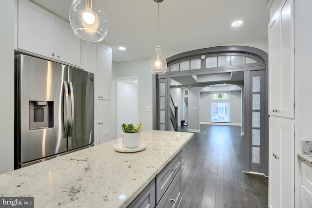 kitchen featuring light stone countertops, dark wood finished floors, stainless steel fridge with ice dispenser, arched walkways, and white cabinets