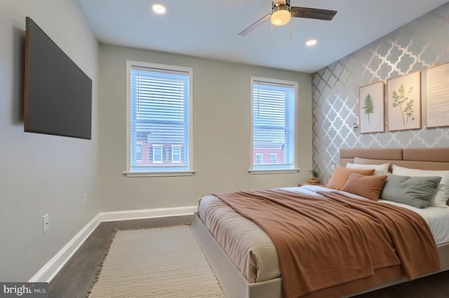 bedroom with baseboards, wallpapered walls, recessed lighting, dark wood-style flooring, and an accent wall