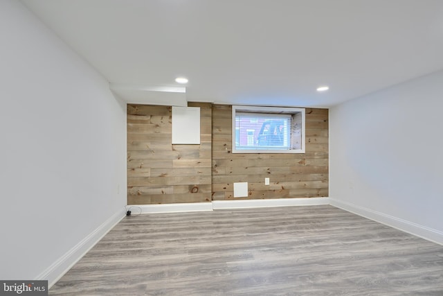 unfurnished room featuring recessed lighting, wood finished floors, baseboards, and wood walls