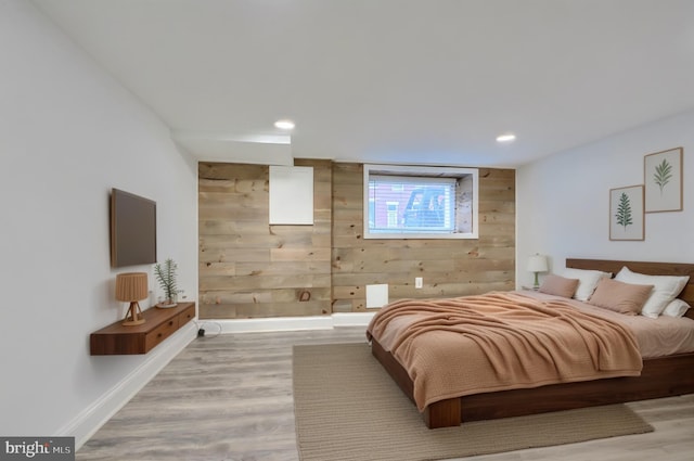 bedroom with recessed lighting, wooden walls, light wood-style flooring, and baseboards