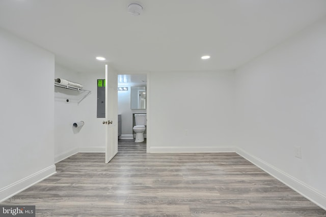 laundry room featuring electric panel, baseboards, wood finished floors, and recessed lighting