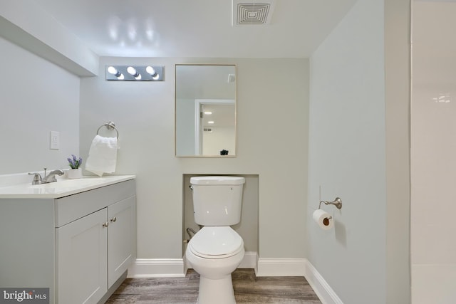 bathroom with visible vents, baseboards, toilet, wood finished floors, and vanity