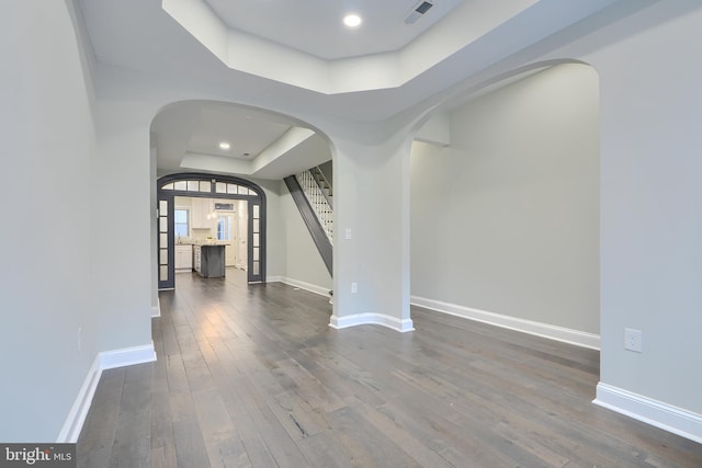 interior space with a tray ceiling, baseboards, visible vents, and dark wood-type flooring