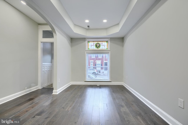 empty room featuring dark wood finished floors, recessed lighting, baseboards, and arched walkways