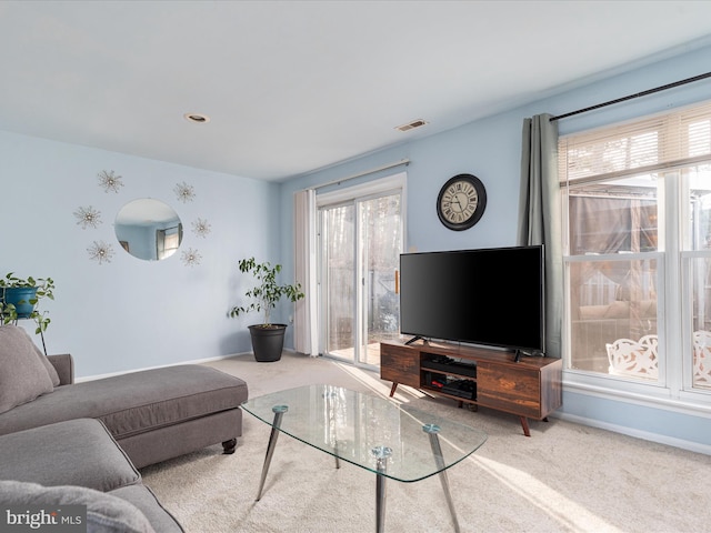 living room featuring a wealth of natural light, carpet flooring, visible vents, and baseboards