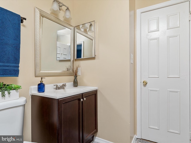 bathroom featuring baseboards, toilet, and vanity