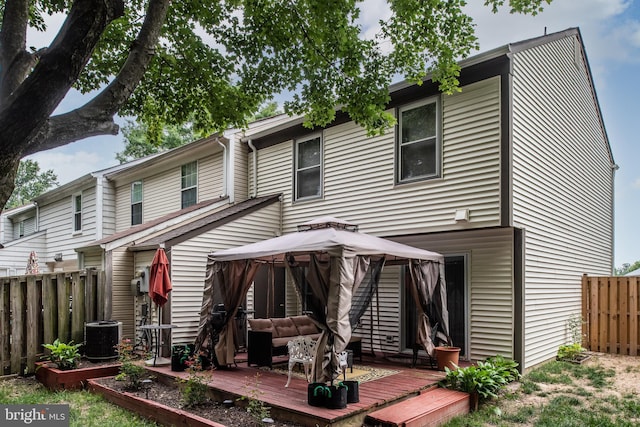 rear view of house featuring a gazebo, a wooden deck, outdoor lounge area, and a fenced backyard