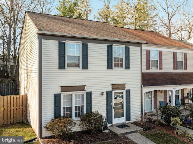 townhome / multi-family property with a shingled roof and fence