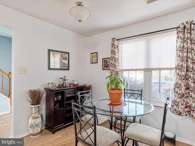 dining area with stairway, baseboards, light wood-style floors, and visible vents