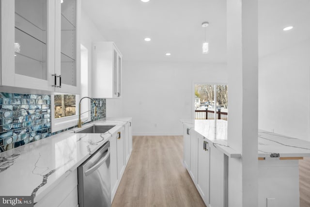 kitchen with tasteful backsplash, a sink, light stone counters, and stainless steel dishwasher