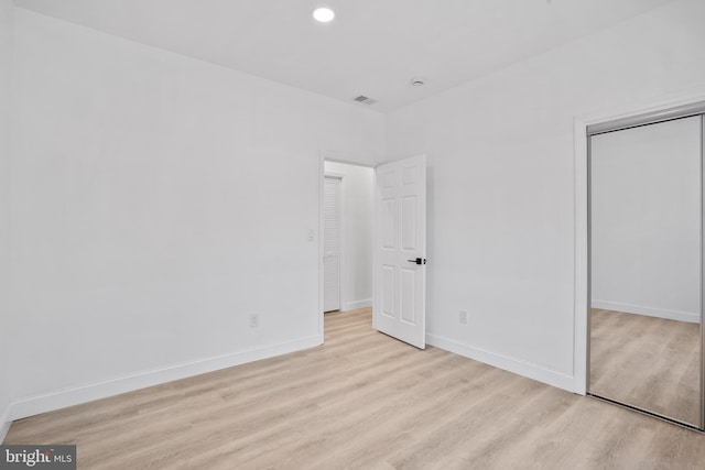 unfurnished bedroom featuring recessed lighting, wood finished floors, baseboards, and a closet