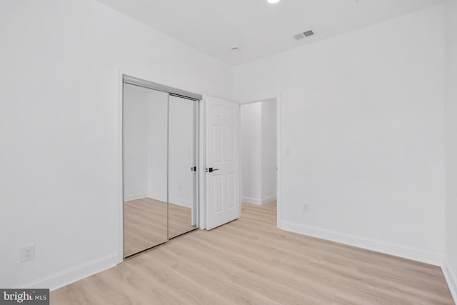 unfurnished bedroom with baseboards, visible vents, a closet, and light wood-type flooring