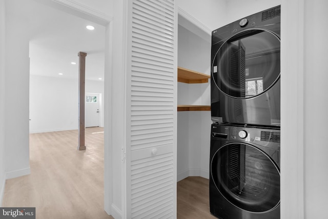 laundry room featuring wood finished floors, baseboards, laundry area, recessed lighting, and stacked washer / dryer