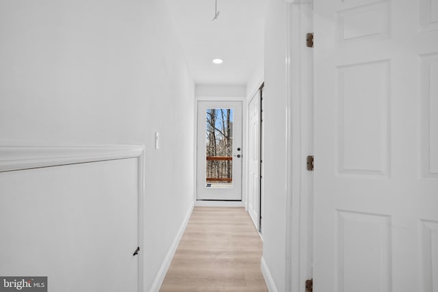 corridor featuring light wood-style flooring and baseboards