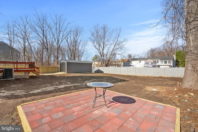 view of patio / terrace featuring a deck, an outbuilding, a storage unit, and a fenced backyard