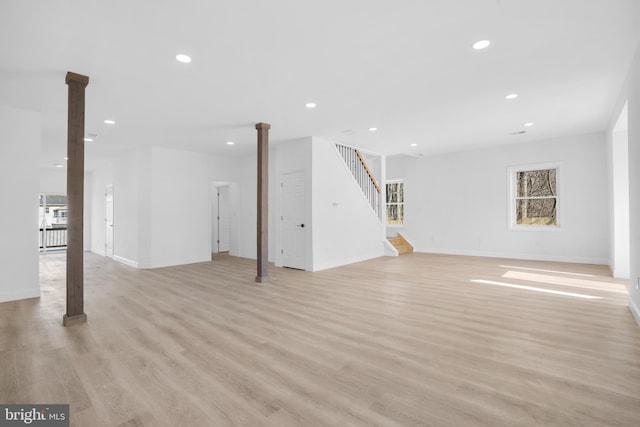 unfurnished living room featuring stairs, recessed lighting, baseboards, and light wood finished floors