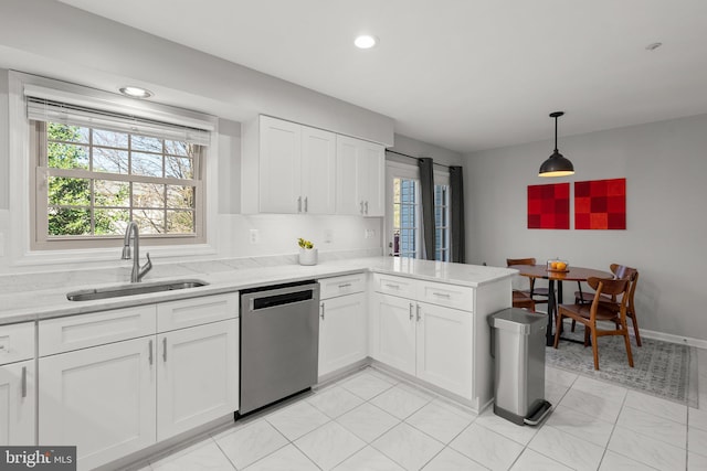 kitchen featuring a sink, a peninsula, plenty of natural light, and dishwasher